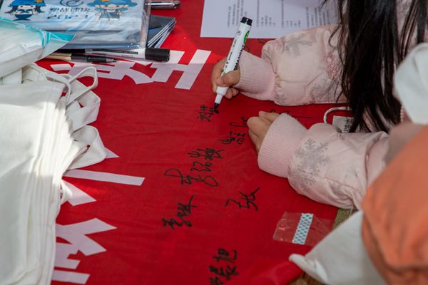 77092a21f0b046a59249fb3ed914a82f.jpg 路人们在横幅上签下自己的名字.jpg